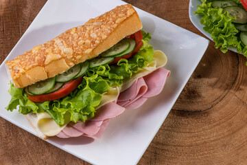 

Natural sandwich with baguette bread. Cheese, ham, lettuce, tomato and cucumber.