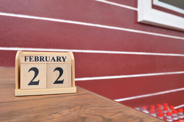 February 22, Number cube with wooden table beside the wall.