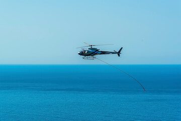 A maintenance helicopter repairing the  coastal path towards the Cinque Terre village of Corniglia in the summertime