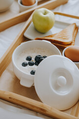 Breakfast in the hotel. Porridge, boiled egg, toast, coffee, porridge with berries on a tray. High quality photo