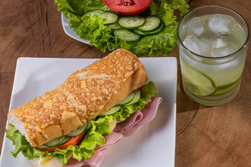 
Natural sandwich with baguette bread. Cheese, ham, lettuce, tomato and cucumber.