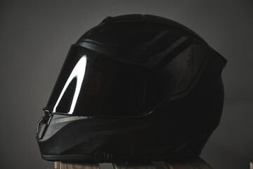 Black motorcycle helmet with a closed visor on a gray background