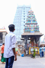 A young man stands with back view on the temple