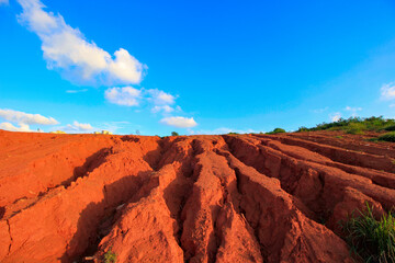 The red land is under the blue sky and white clouds.