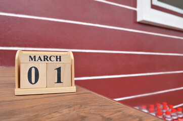 March 1, Number cube with wooden table beside the wall.