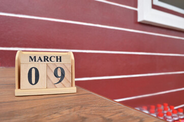 March 9, Number cube with wooden table beside the wall.