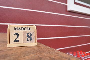 March 28, Number cube with wooden table beside the wall.