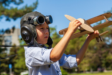 The concept of a dream is to become a pilot, boy in the form of an aircraft pilot ; Happy child In a helmet with glasses and binoculars, playing with toy airplane . toned