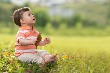 1 year old caucasian boy sitting on green lawn