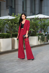 Fototapeta premium Bussines lady in red suit stands near office. Soft selective focus.