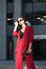 Bussines lady in red suit stands near office. Soft selective focus.