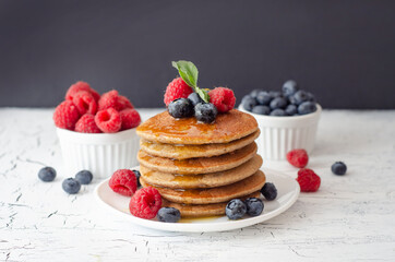 Pancakes with forest fruits berries on white table. Healthy breakfast. Blueberries, raspberries on pancakes.