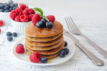 Pancakes with forest fruits berries on white table. Healthy breakfast. Blueberries, raspberries on pancakes.
