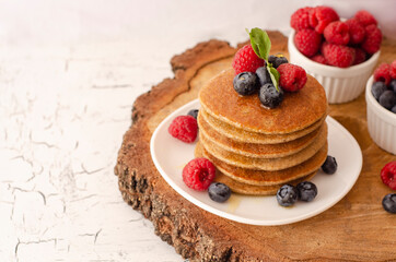 Pancakes with forest fruits berries on white table. Healthy breakfast. Blueberries, raspberries on pancakes.