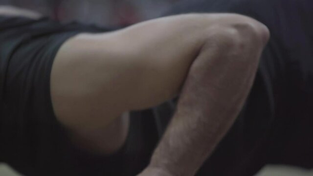 Close-up arm of strong sportsman pushing up. Unrecognizable Caucasian man exercising in gym. Workout of athletic muscular body-builder in sports club.