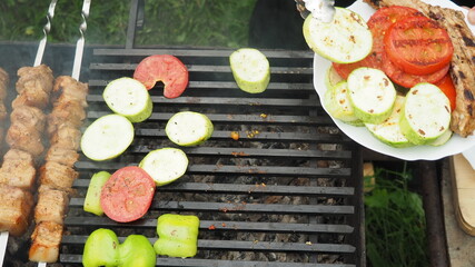 the cook removes vegetables and meat from the grill with tongs on a plate. delicious food.
