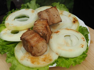 the cook removes pieces of pork skewer from the brisket on lettuce leaves and toasted onions. grilled dishes.