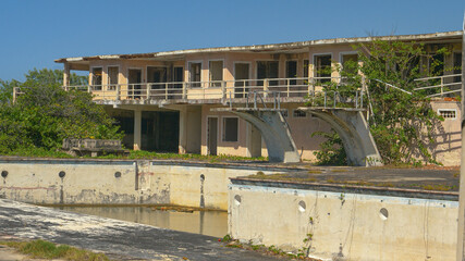 Fototapeta na wymiar Abandoned hotel and pool decay in the scorching heat in the idyllic Caribbean.