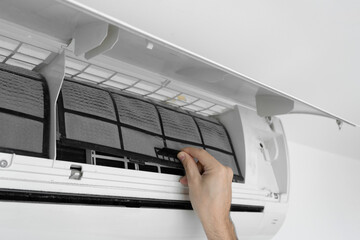 The guy cleans the filter of the home air conditioner from dust. Very dirty air conditioner filter....