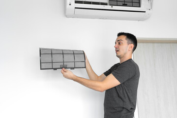 The guy cleans the filter of the home air conditioner from dust. Very dirty air conditioner filter....