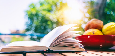 Book on the table and page close-up with fruit plate. Summer Reading Concept