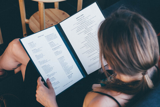 High Angle View Of Woman Reading Menu At Restaurant