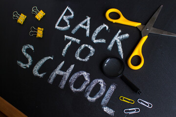 Inscription back to school. On a chalky black board. Handwritten. Stationery school accessories.