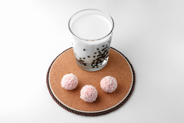 pink chocolate candy and a glass of milk on a white background. candy ball macro. isolate