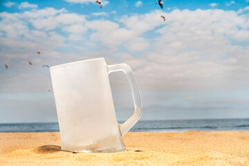  empty and ice cold beer mug on the beach with seagulls flying