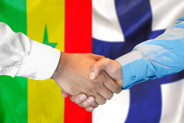 Handshake on Senegal and Finland flag background. Support concept.