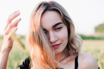 Young, slender girl embroidered dress in a large wheat field at sunset