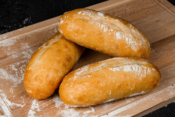 fresh white bread on a cutting board with flour on a black wooden table
