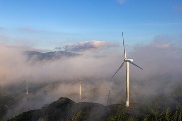 High in the mountains are wind turbines at sunrise and sunset and a sea of clouds