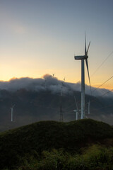 Fototapeta premium High in the mountains are wind turbines at sunrise and sunset and a sea of clouds
