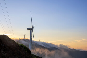Obraz premium High in the mountains are wind turbines at sunrise and sunset and a sea of clouds