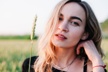 Young, slender girl embroidered dress in a large wheat field at sunset