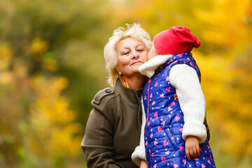Happy senior lady and a little toddler girl, grandmother and granddaughter, enjoying a walk in the park. Child and grandparent. autumns day. Grandmother and little girl happy together in the garden