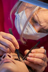 Eyelash Extension Procedure. Woman Eye with Long Eyelashes. Lashes. With Mask Medicinal Covid.