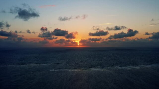 Beautiful aerial drone shot of a serene ocean sunrise at Well Beach near Joao Pessoa on a warm summer morning with the water below and golden clouds on the skyline.