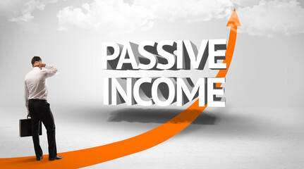 Fototapeta premium Rear view of a businessman standing in front of PASSIVE INCOME inscription, successful business concept