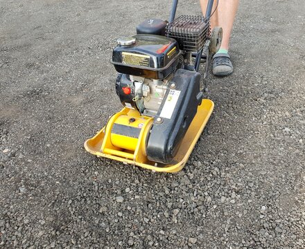 Worker using vibrating plate.
