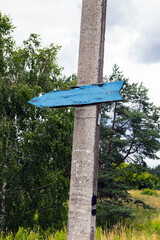 Wooden, old arrow pointer to a concrete pillar.