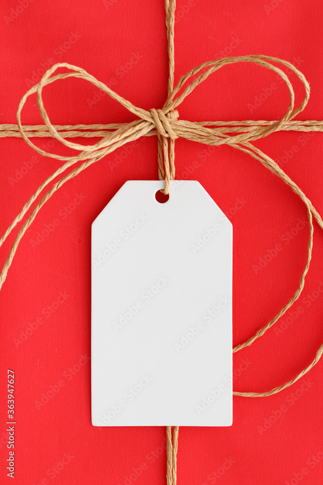 Sticker White gift tag mockup on a red christmas gift.