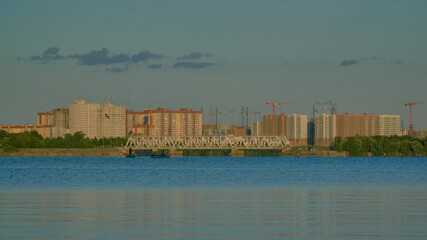 Naklejka premium View of residential buildings in golden light on the Voronezh reservoir from the right bank in summer