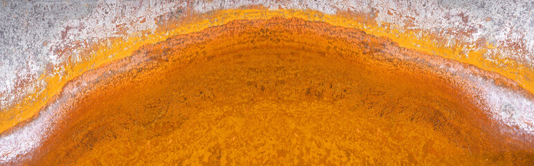 Abstraktes Halbkreis Muster von orangem Rost in vertrocknetem Wasser in einer hellen Metallschale
