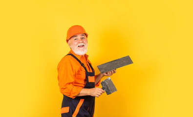 plaster trowel spatula on yellow drywall plasterboard. Plasterer in working uniform plastering. man...