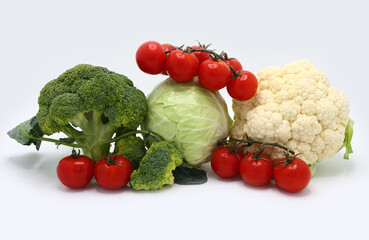 Head of cabbage, inflorescences of broccoli and cauliflower and red ripe tomatoes on a light background. Natural product. Natural hue. Close-up.