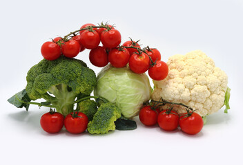 Head of cabbage, inflorescences of broccoli and cauliflower and red ripe tomatoes on a light background. Natural product. Natural hue. Close-up.