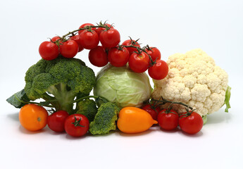 Head of cabbage, inflorescences of broccoli and cauliflower and red and yellow ripe tomatoes on a light background. Natural product. Natural hue. Close-up.