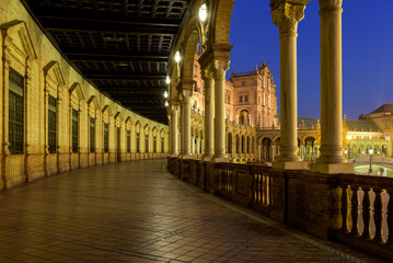 Spanish Square - A wide-angle dusk view of the illuminated ground-level portico curving along the semi-circular brick building at Spanish Square - Plaza de España, Seville. Andalusia, Spain.